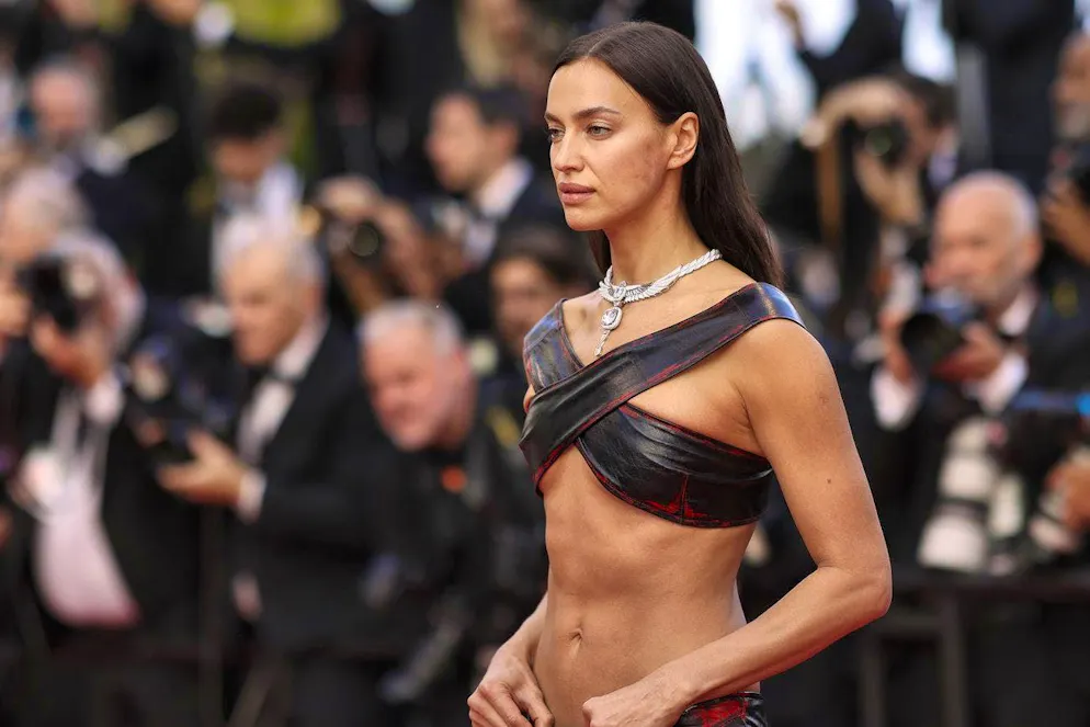 Model Irina Shayk in Cannes 2023, covering her chest with two crossed leather strips and leaving the rest of her upper body bare.