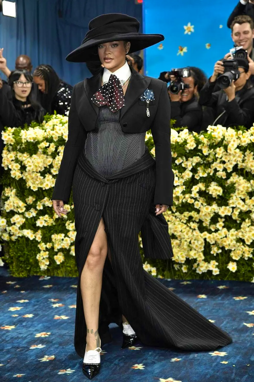 Rihanna - la sfilata di moda in gravidanza è iniziata!. Né l'enorme cappello né la cravatta di raso a pois hanno distolto l'attenzione dalla lieta notizia, sottilmente messa in scena sotto il bustier.