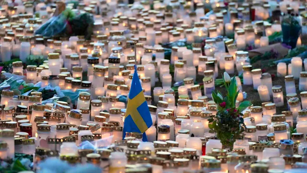 ARCHIVE - A Swedish flag stands among candles and flowers at a makeshift memorial near the crime scene after the deadly shooting that killed several people on Tuesday (04.02.2025). Photo: Sergei Grits/AP/dpa