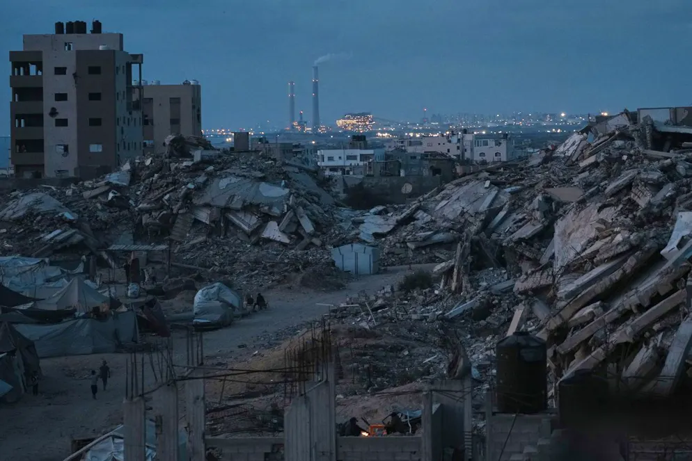 Des Palestiniens déplacés par l'offensive aérienne et terrestre israélienne sur la bande de Gaza se tiennent debout, entourés de bâtiments détruits, au crépuscule, dans un quartier de la ville de Gaza, le lundi 2 juin 2025. (AP Photo/Jehad Alshrafi)