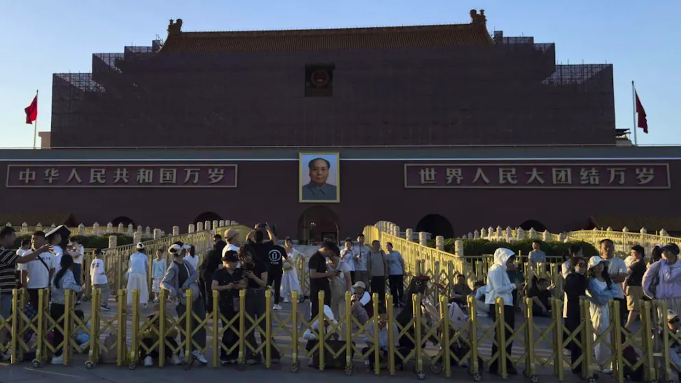 Des visiteurs se rassemblent devant la porte de Tiananmen, recouverte de cadres et d'échafaudages pour des travaux de rénovation, en attendant la cérémonie de descente du drapeau à la veille de l'anniversaire du 4 juin, à Pékin.