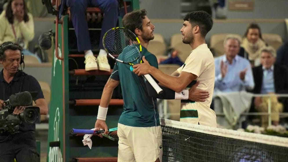 Carlos Alcaraz (in white) accepts the congratulations and wishes Lorenzo Musetti a speedy recovery