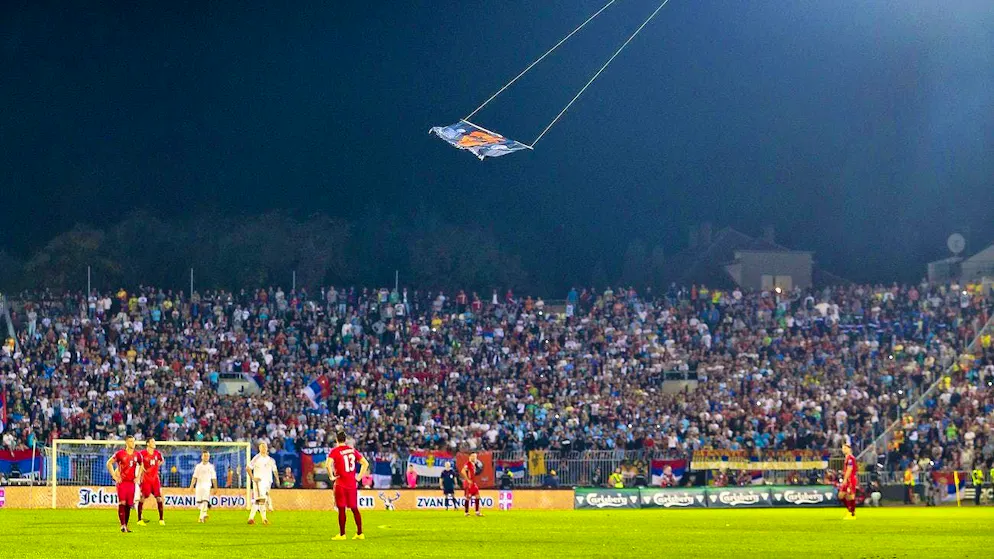 Tirana si prepara alla partita fra nazionali più pericolosa d'Europa. La bandiera con i simboli albanesi sventola sullo stadio controllata a distanza da un drone.