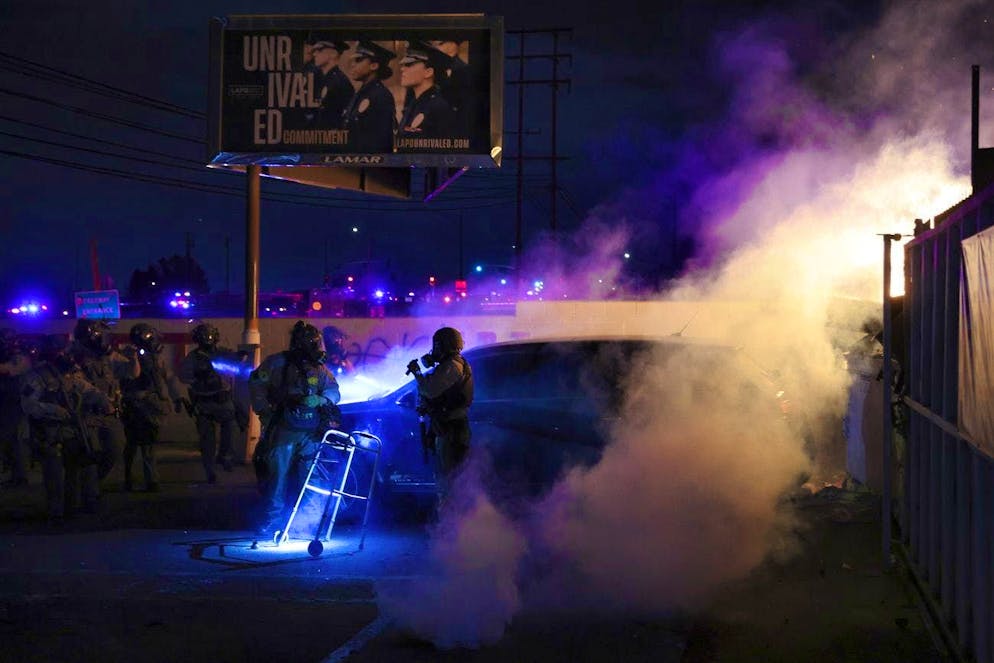 Law enforcement investigate a car with a person inside during a protest in Compton, Calif., Saturday, June 7, 2025, after federal immigration authorities conducted operations. (AP Photo/Ethan Swope)
