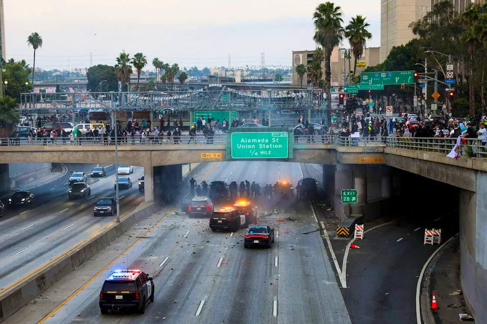Protests L.A.. Police officers take cover as activists throw stones and fireworks at their vehicles.