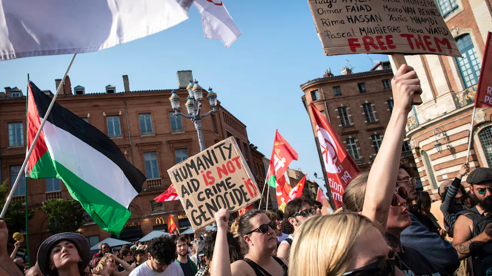 Des manifestants brandissent des pancartes et un drapeau palestinien lors d'une manifestation de soutien aux activistes à bord d'un bateau arrêté par les forces israéliennes en route pour acheminer de l'aide à Gaza, à Toulouse, dans le sud-ouest de la France, le 9 juin 2025.