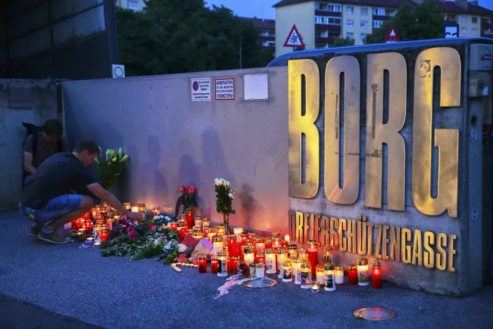 Un uomo posiziona una candela all'ingresso di una scuola dopo una sparatoria mortale avvenuta lì, a Graz, in Austria, martedì 10 giugno 2025.