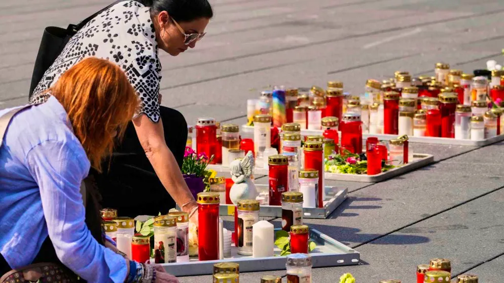 People light candles in the main square after a former student killed several people and injured many others in a school the day before taking his own life. Photo: Darko Bandic/AP/dpa