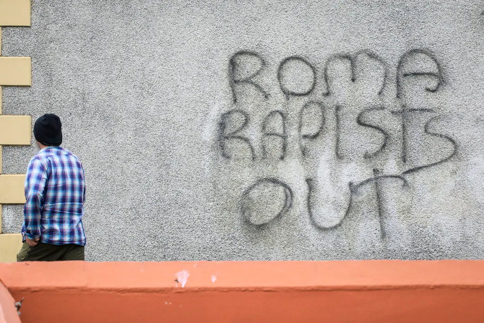 Un piéton passe devant un graffiti sur lequel on peut lire « Dehors les violeurs roms » après une deuxième nuit de manifestations anti-immigration à Ballymena, en Irlande du Nord, le 11 juin 2025.