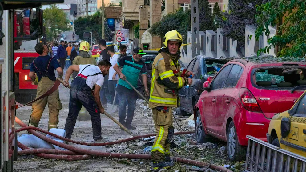 Firefighters and people clear the scene of an explosion in a residential complex after the Israeli attack on the Iranian capital Tehran.