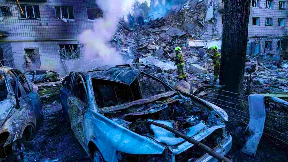 Rescue workers extinguish a fire at a car in front of a multi-storey apartment building destroyed by a Russian attack in the Ukrainian capital. Photo: Evgeniy Maloletka/AP/dpa