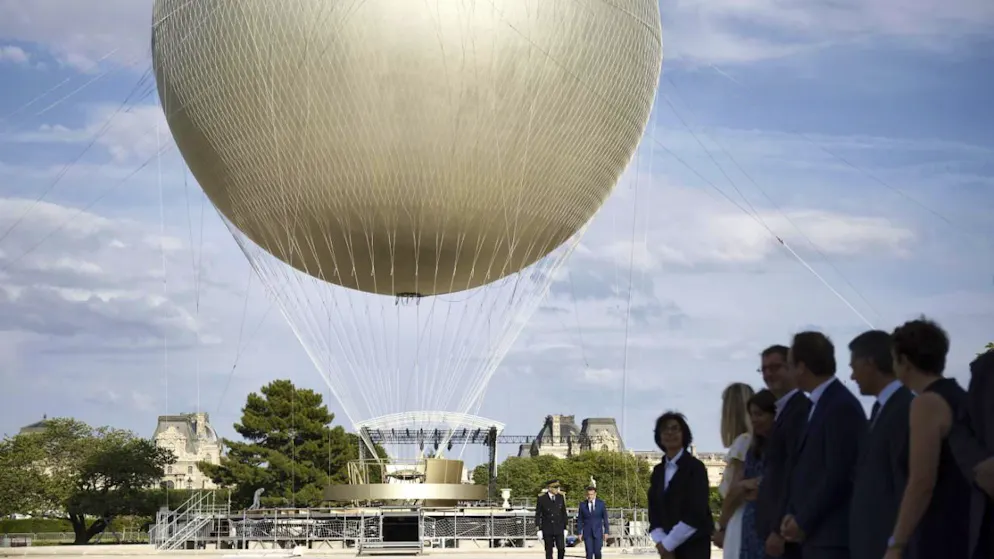 Le président français Emmanuel Macron, à droite en arrière-plan, visite le chantier de réinstallation de la vasque olympique au jardin des Tuileries à Paris.
