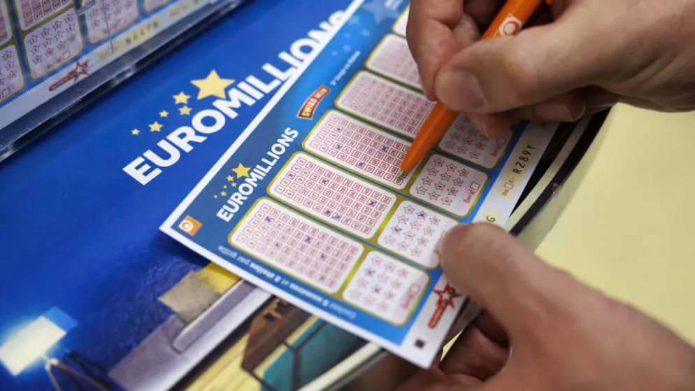 Un homme coche des numéros sur un bulletin de l'Euro Millions de la Loterie Romande .
