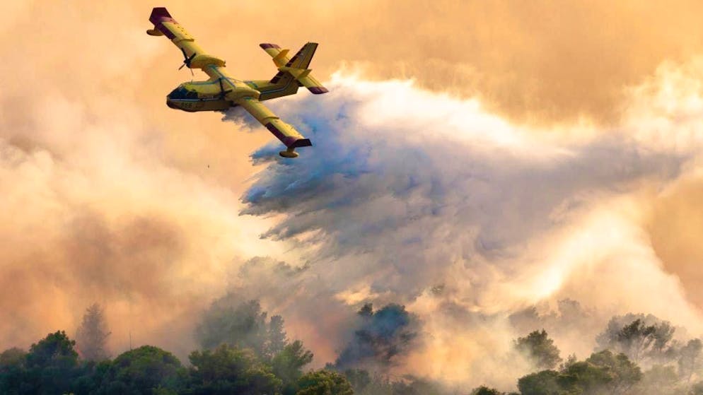 Forest fire Croatia. A fire-fighting plane sprays water to extinguish a forest fire on the island of Ciovo.