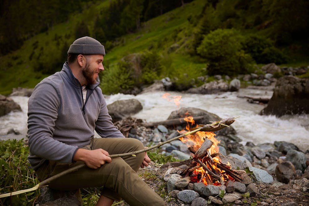 Sandro Zinggeler grill a trout above the fire.