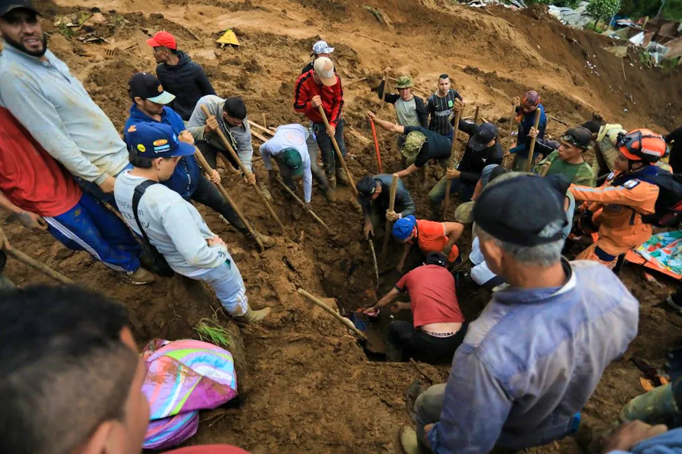 Des habitants aident les équipes de secours à retrouver les victimes du glissement de terrain, le 25 juin 2025, dans la banlieue de Medellín.