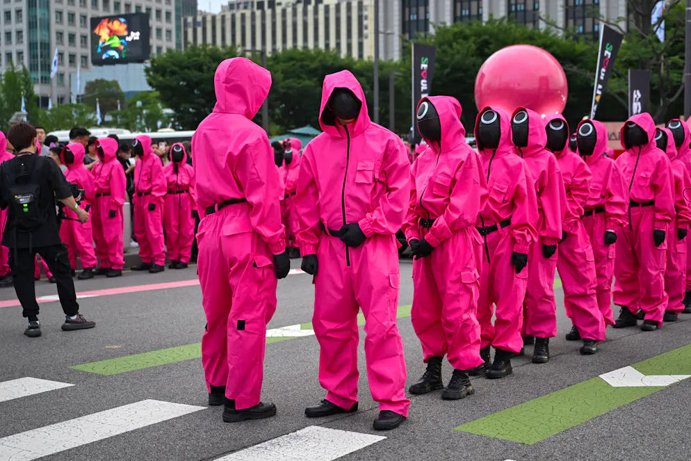 Les gardes de Squid Game défilent lors d’un événement organisé pour la sortie de la troisième saison de la série sud-coréenne Squid Game, sur la place Gwanghwamun à Séoul, le 28 juin 2025.