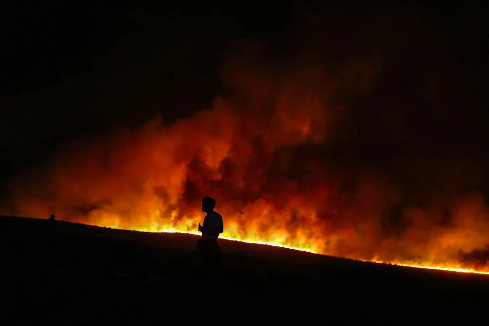 Une personne observe un incendie de forêt dans le district de Çeşme à Izmir, en Turquie, le 3 juillet 2025 (archives).