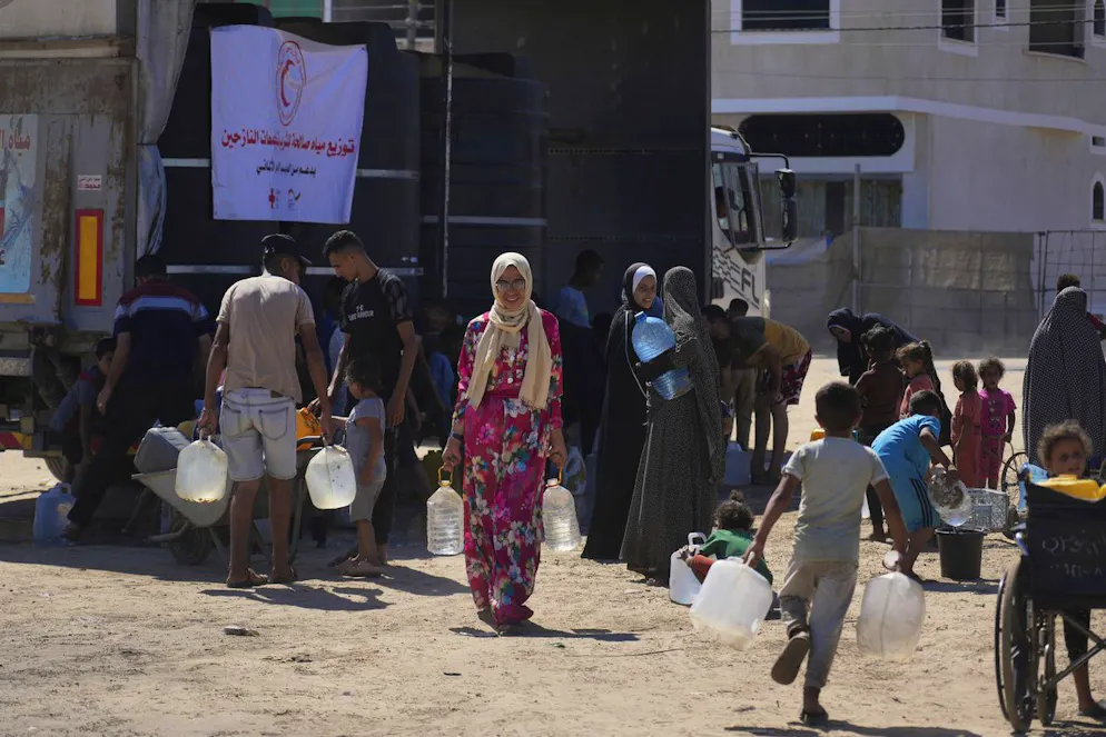 Palestinesi trasportano contenitori per l'acqua in un campo per sfollati a Deir al-Balah, nella Striscia di Gaza.