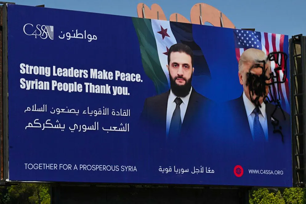 Une photo montre une affiche promotionnelle portant le portrait du président intérimaire syrien Ahmad al-Sharaa et un portrait détérioré du président américain Donald Trump, à Damas, le 9 juillet 2025. 