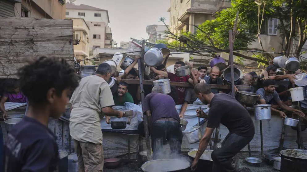 Palestinesi in fila per ottenere cibo donato in una cucina comunitaria a Gaza City