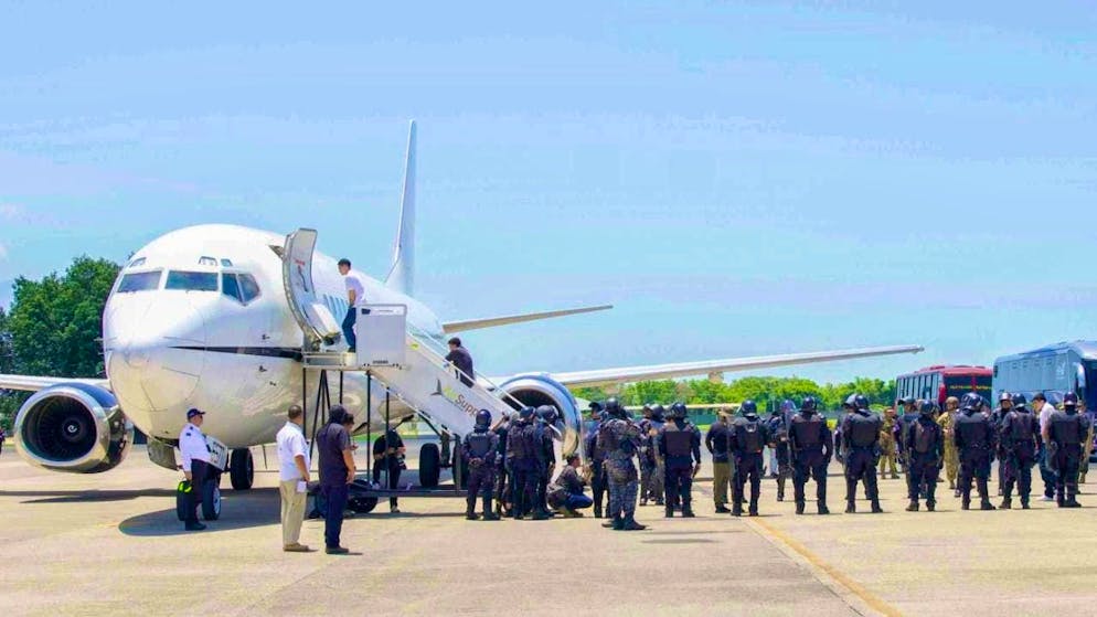 HANDOUT - This photo released by El Salvador's presidential press office shows men identified by the Salvadoran government as Venezuelans who were detained by the U.S. government months ago and flown to El Salvador. They board a Venezuelan airplane bound for Venezuela while soldiers stand by at Oscar Arnulfo Romero International Airport. Photo: Uncredited/El Salvador's presidential press office/AP/dpa - ATTENTION: For editorial use only and only with full attribution to the above credit