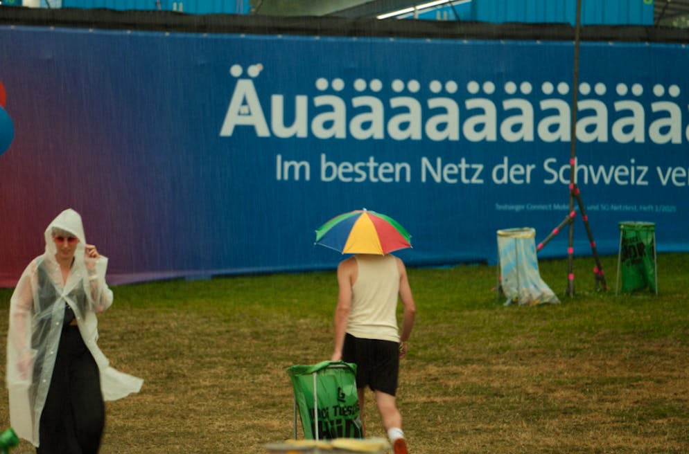 Regen am Gurten-Festival. Die Besuchenden sind mit Pelerine und Schirm ausgerüstet. 
