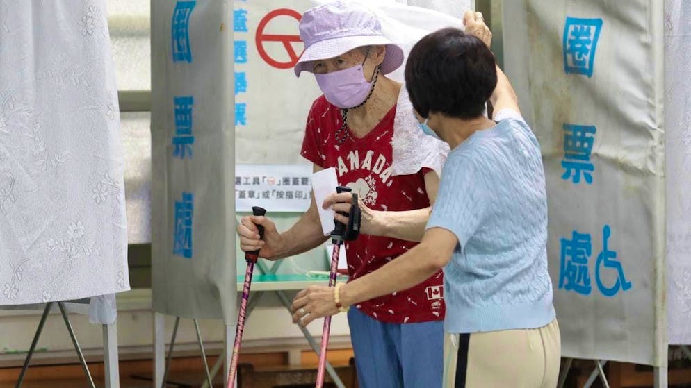 A woman steps out of a voting booth at a polling station in Taipei, Taiwan. Photo: Chiang Ying-ying/AP/dpa