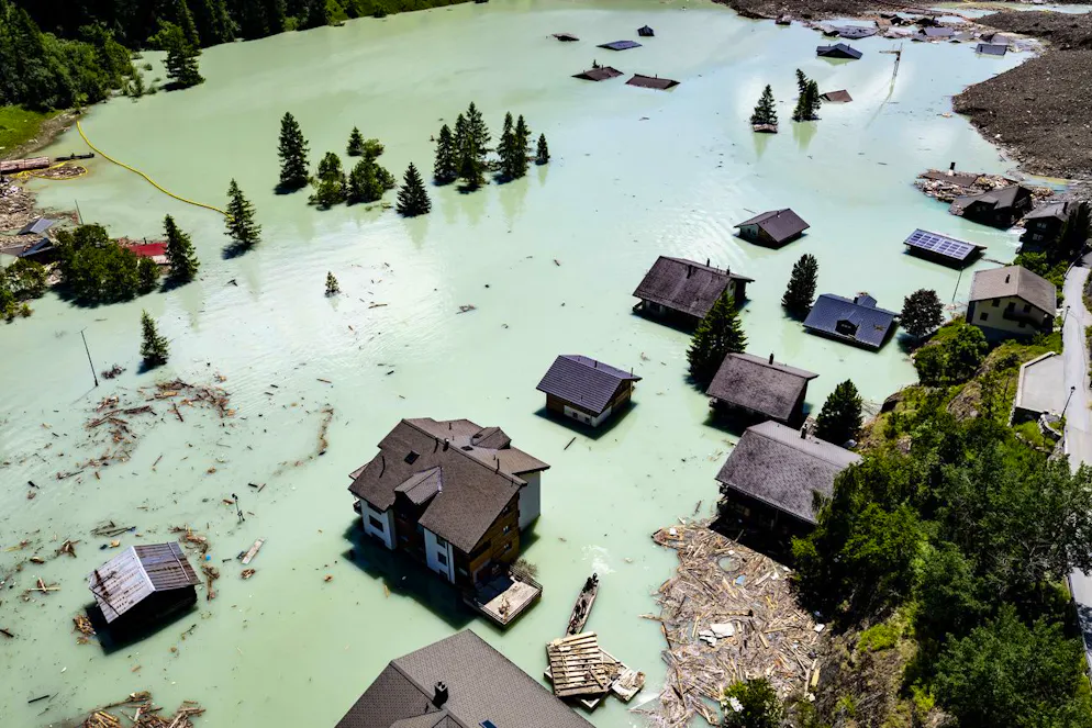 Une vue aerienne montre deux barques qui naviguent, sur le lac forme apres l'eboulement, avec des militaires de l'Armee suisse qui enlevent les debris a l'aide d'un barrage flottant le mardi 24 juin 2025 a Blatten dans le Loetschental (archives).
