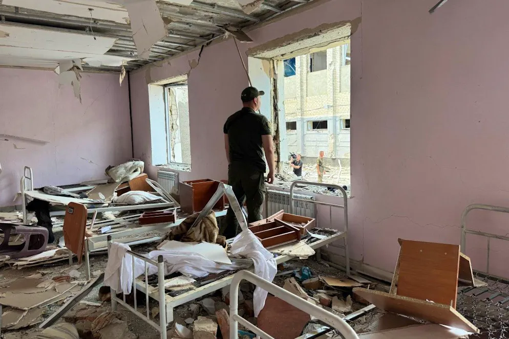 Un membre des forces de l’ordre ukrainiennes regarde par une fenêtre brisée à l’intérieur d’un bâtiment détruit de la colonie pénitentiaire de Bilenkivska, à la suite d’une frappe aérienne survenue à Bilenke, dans la région de Zaporijjia, le 29 juillet 2025.