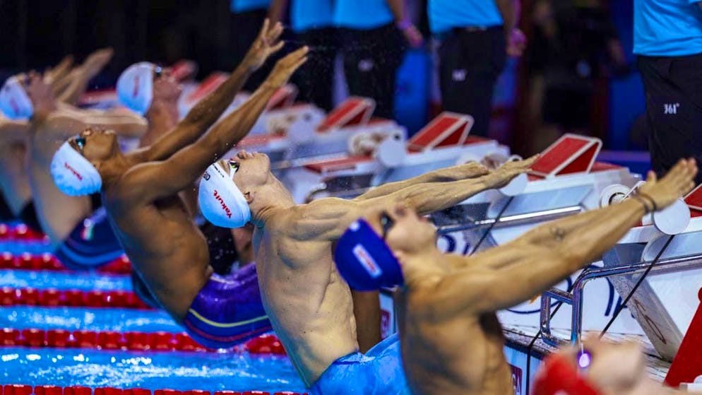 Roman Mityukov with the white swimming cap in the foreground gets going.