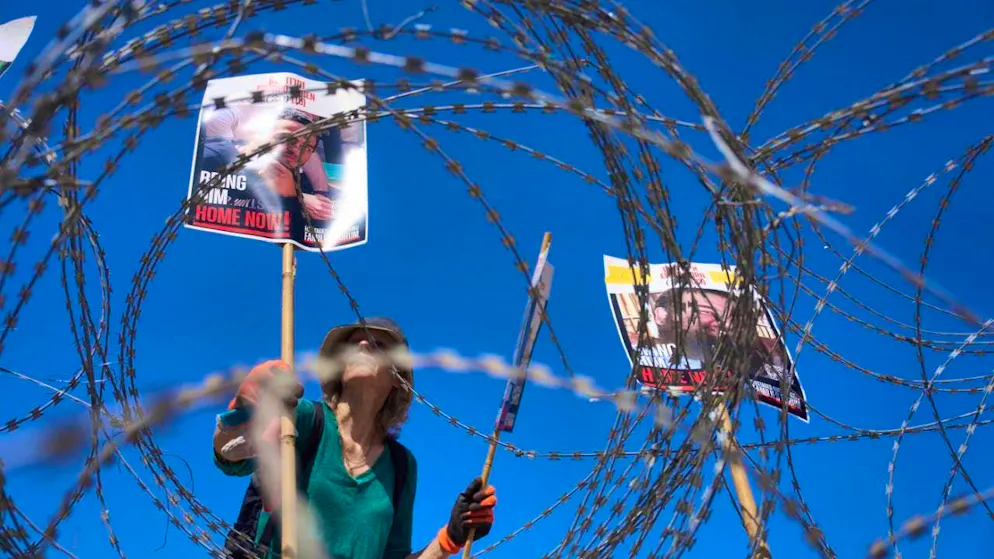 dpatopbilder - A woman places pictures of hostages Nimrod Cohen (l) and Eitan Horn, held captive by Hamas in the Gaza Strip, on a barbed wire during a protest by families in the hostages' square. Photo: Ariel Schalit/AP/dpa
