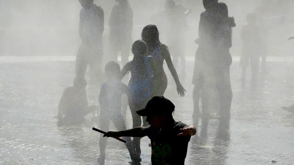 Menschen kühlen sich in Madrid bei heißem Wetter in einem Brunnen ab. Foto: Paul White/AP/dpa/Archiv