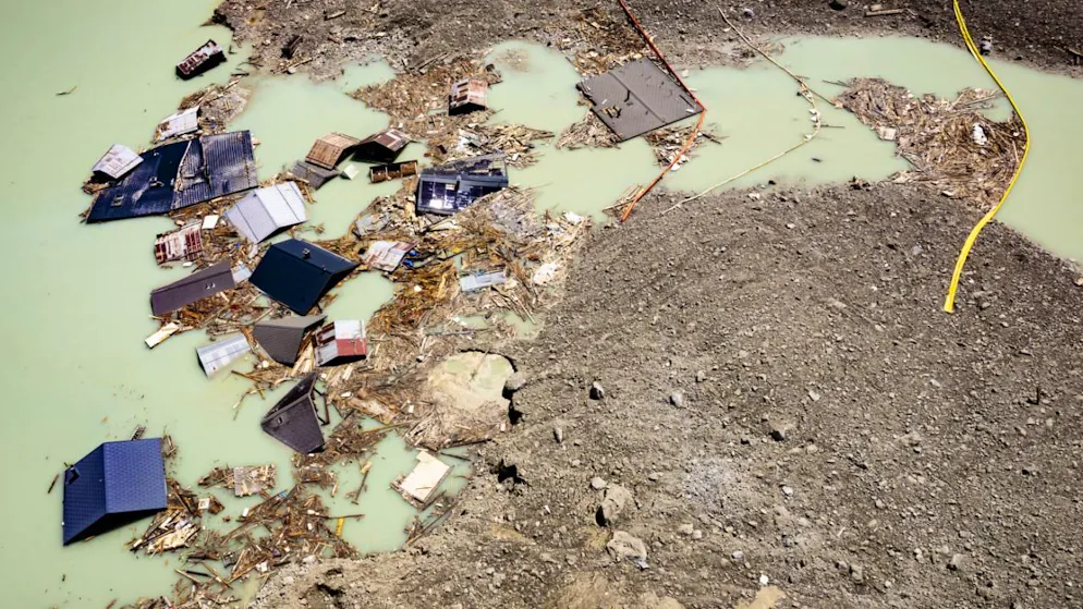Legname e tetti di edifici nel lago a monte del cono di detriti in un'immagine del 24 giugno.