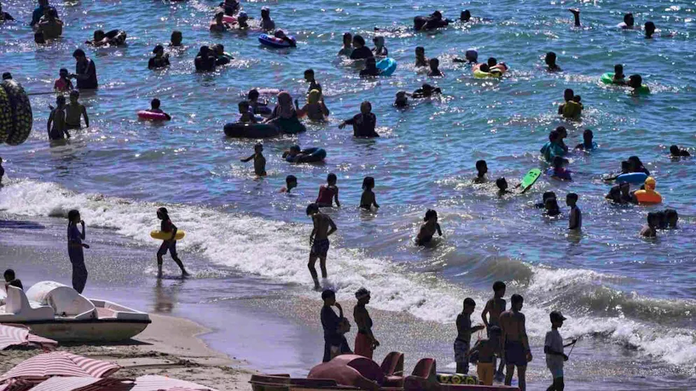 ARCHIVIO - Le persone trascorrono il tempo sulla spiaggia vicino alla città di Alessandria, in Egitto. Foto: Amr Nabil/AP/dpa