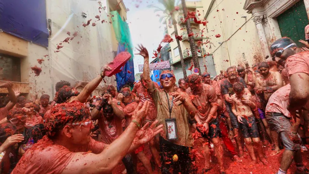 Während der jährlichen Tomatenschlacht «Tomatina» in der Region von Valencia bewerfen sich die Feiernden gegenseitig mit Tomaten. Foto: Alberto Saiz/AP/dpa