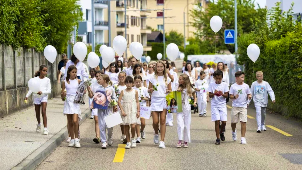 Many children were among those taking part in the funeral march in Corcelles NE. They carried white balloons, white roses and photos of the victims.
