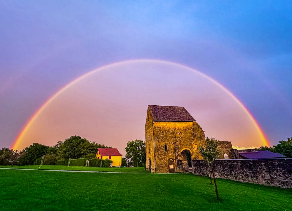 Die Ruine des ehemaligen Cluniazenser Priorats Rüeggisberg wird von einem Regenbogen erleuchtet.