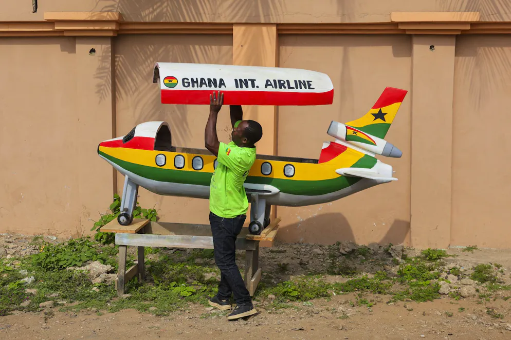 Eric Kpakpo Adotey espone una bara a forma di aeroplano davanti al suo negozio a La, Accra, Ghana.