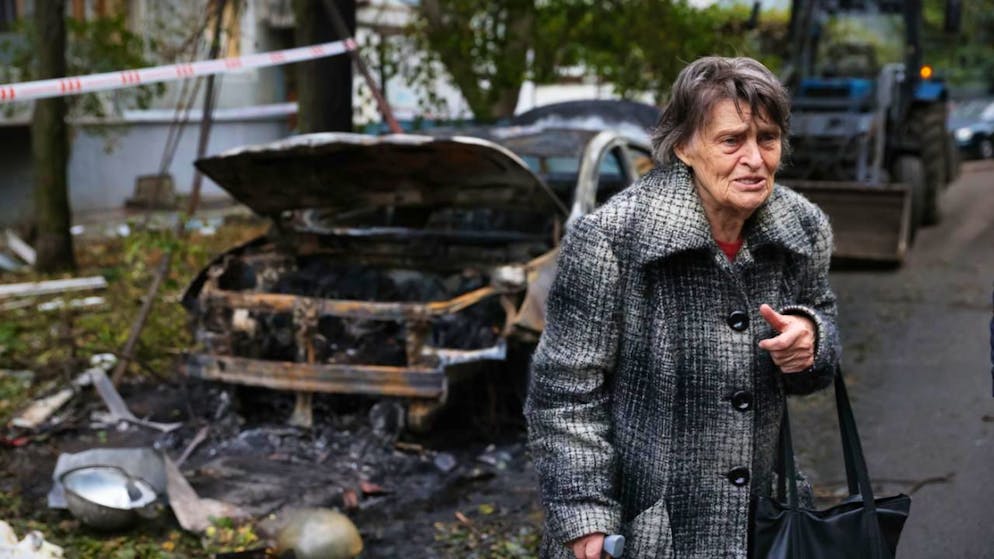 dpatopbilder - Eine ältere Frau neben einem zerstörten Auto in Saporischschja. Foto: Kateryna Klochko/AP/dpa