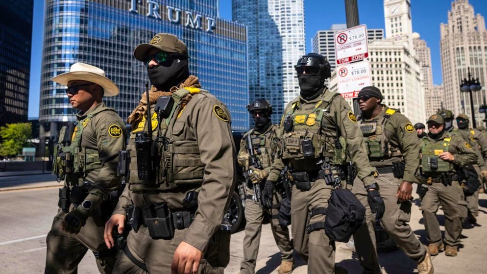 ARCHIV - Bundesbeamte der US-Einwanderungs- und Zollbehörden und der US-Zollbehörde US Customs and Border Protection gehen den West Wacker Drive entlang an einem Trump-Gebäude vorbei. Foto: Ashlee Rezin/Chicago Sun-Times/dpa - ACHTUNG: Nur zur redaktionellen Verwendung und nur mit vollständiger Nennung des vorstehenden Credits
