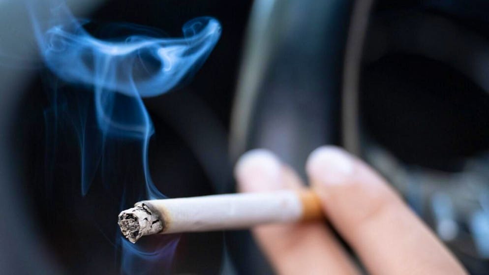 ARCHIV - Eine Frau sitzt in einem PKW und hält eine Zigarette. Foto: Sebastian Kahnert/dpa