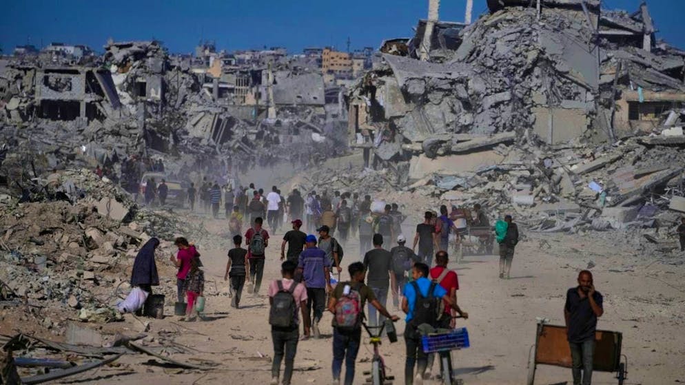 dpatopbilder - Palestinians walk past destroyed buildings as they return to their homes in the Zeitoun neighborhood of Gaza. Photo: Jehad Alshrafi/AP/dpa