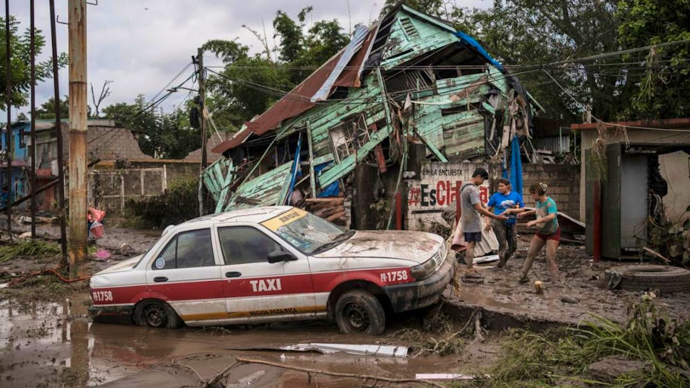 Nachbarn versammeln sich um ein beschädigtes Haus nach heftigen Regenfällen in Poza Rica im mexikanischen Bundesstaat Veracruz. Foto: Felix Marquez/AP/dpa