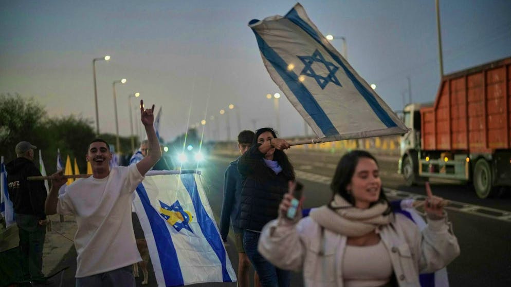 People gather outside the Reim Israeli military camp on the edge of the Gaza Strip, where the Israeli hostages will be taken after their release on Monday morning.