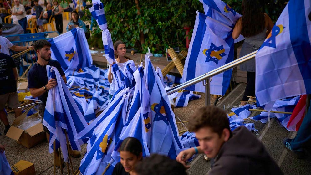 Volunteers prepare Israeli flags as people gather in Tel Aviv's "Hostages Square" ahead of Monday morning's expected hostage handover. (October 12, 2025)