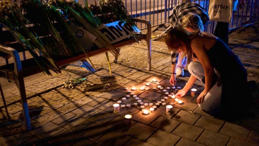 dpatopbilder - A woman lights candles in front of the Abu Kabir Forensic Institute, where the identification of bodies held and killed by Hamas in the Gaza Strip is being carried out. Photo: Emilio Morenatti/AP/dpa