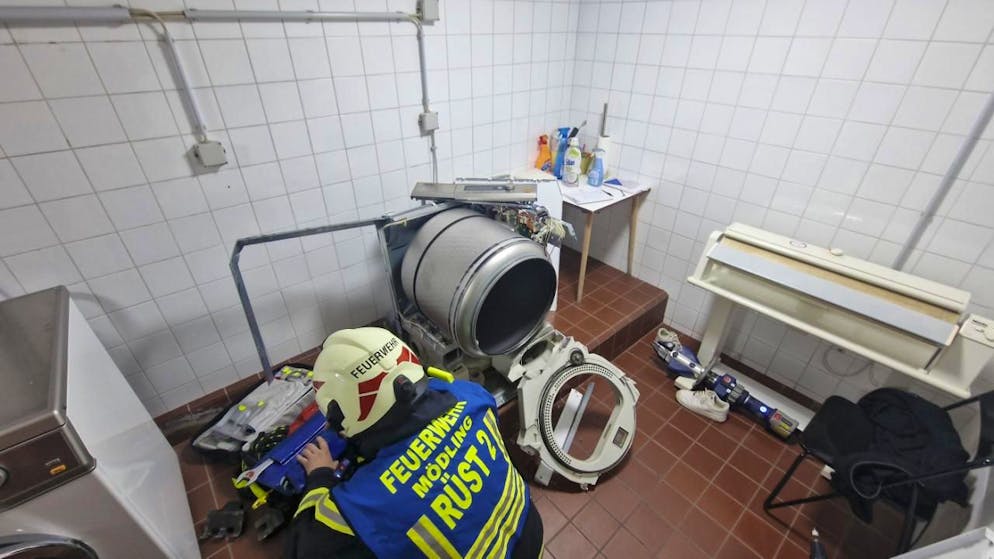 HANDOUT - Ein Mitarbeiter der Feuerwehr Mödling arbeitet in einem Raum, in dem eine 13-Jährige in einen Wäschetrockner geklettert war und sich nicht mehr selbst aus dem Gerät befreien konnte. Foto: Unbekannt/FFMOEDLING.AT/APA/dpa - ACHTUNG: Nur zur redaktionellen Verwendung im Zusammenhang mit der aktuellen Berichterstattung und nur mit vollständiger Nennung des vorstehenden Credits