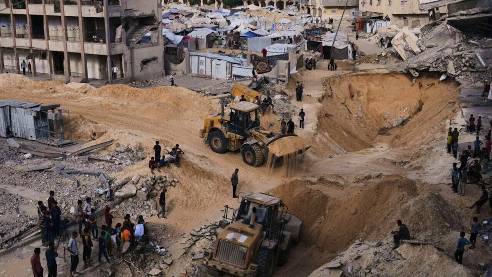 Des Palestiniens regardent des membres du groupe militant Hamas rechercher les corps des otages dans une zone de la ville de Hamad, à Khan Younis, dans le sud de la bande de Gaza.