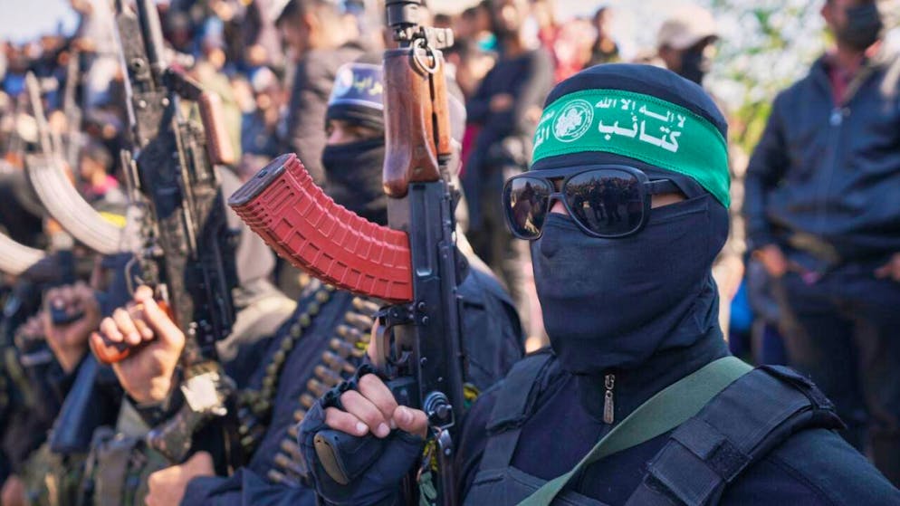 ARCHIV - Kämpfer der Hamas und des Islamischen Dschihad halten ihre Waffen, während Autos mit den Deutsch-Israelis Gadi Moses und Arbel Yahud, die seit dem 7. Oktober 2023 von der Hamas im Gazastreifen als Geiseln festgehalten wurden, zur Übergabe an das Rote Kreuz  eskortiert werden. Foto: Abdel Kareem Hana/AP/dpa